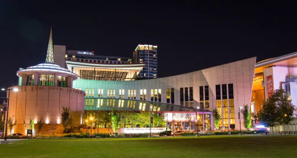 Country music hall of fame viewed across the lawn at night with lights