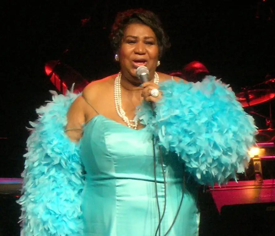 Aretha Franklin in green dress on stage singing