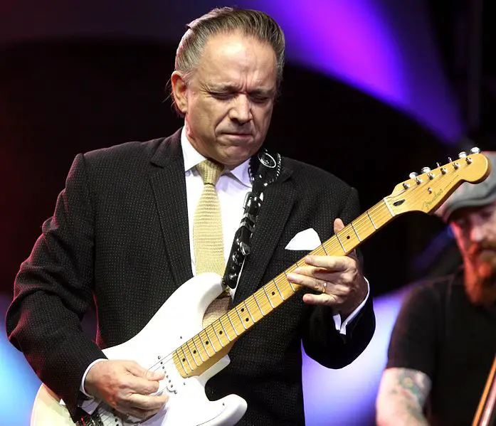 Jimmie Vaughan playing guitar in concert with eyes closed
