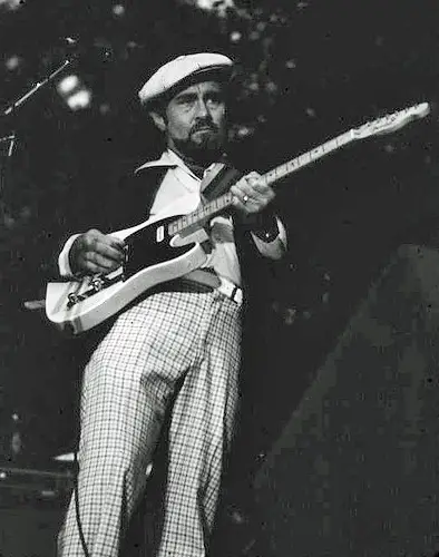 Roy Buchanan playing guitar on stage with white cap