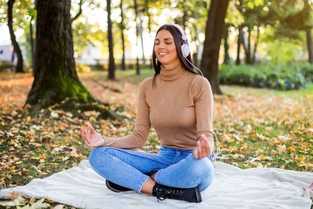 Lady meditating in forest with headphones
