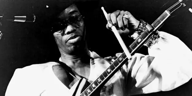 Photo of Johnny Watson playing guitar with a drumstick - Image source: https://www.premierguitar.com/lessons/johnny-guitar-watsons-stinging-blues