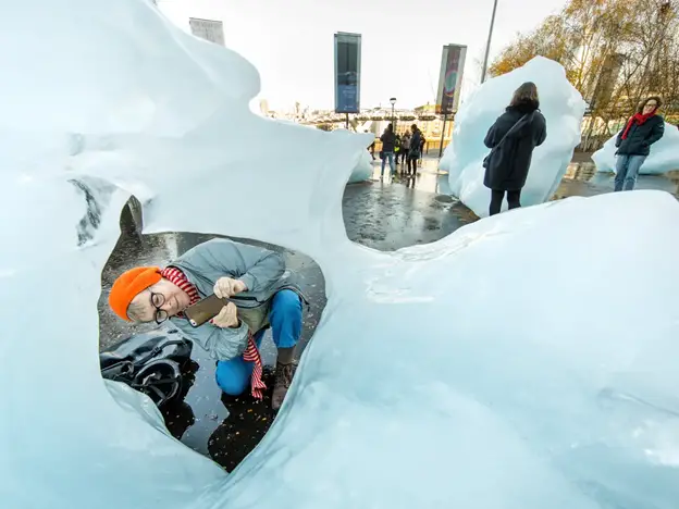 Iceburgs in central london with woman taking a photo - Image source: https://www.theguardian.com/artanddesign/2018/dec/11/icebergs-ahead-olafur-eliasson-brings-the-frozen-fjord-to-britain-ice-watch-london-climate-change