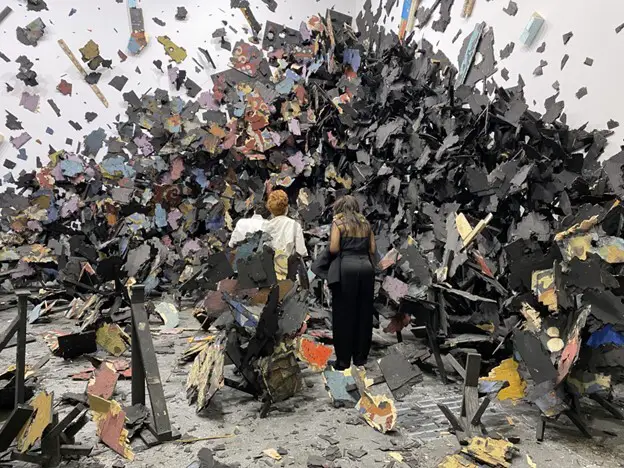 3 people standing in the middle of  a piece of abstract art-Image source: https://news.artnet.com/market/in-pictures-see-the-best-of-art-basel-unlimited-2022-from-a-painting-made-of-hardware-store-finds-to-a-shipping-container-turned-sculpture-2129414