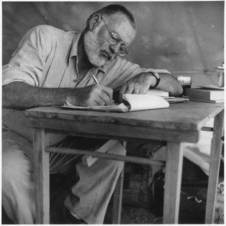 Photo: Look Magazine. Ernest Hemingway Writing at Campsite in Kenya