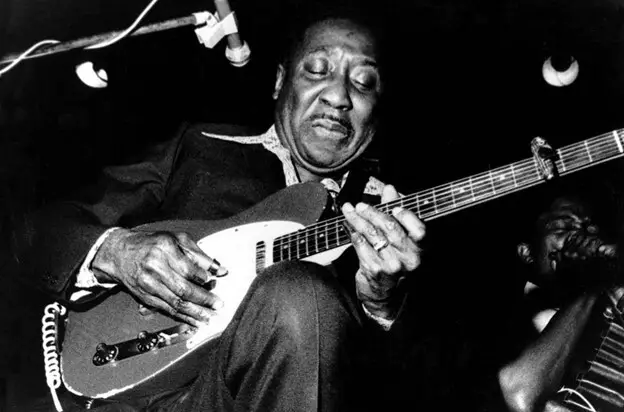 Muddy Waters playing guitar on his knee 