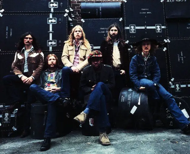 Photo shoot of the Allman Brothers posing in front of their equipment.
