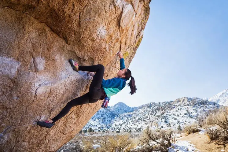woman rock climber on the underside of a huge boulder
