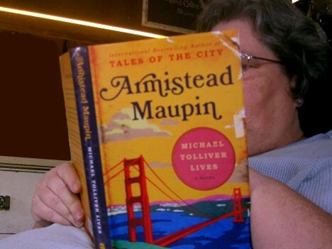 A reader holding one of the later books in the Tales of the City series.