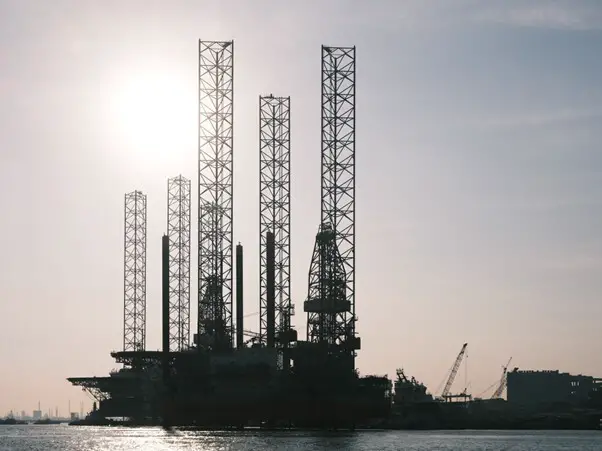 silhouette of an oil rig in harbour with grey sky background