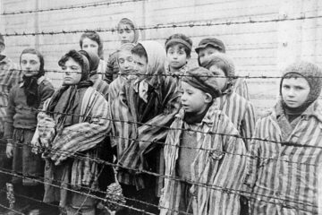 photo of prisoners behind barbed wire in Auschwitz