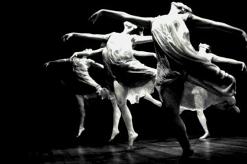 group of modern dancers in black and white, flying through the air