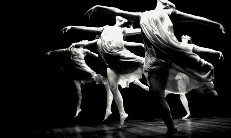 group of modern dancers in black and white, flying through the air